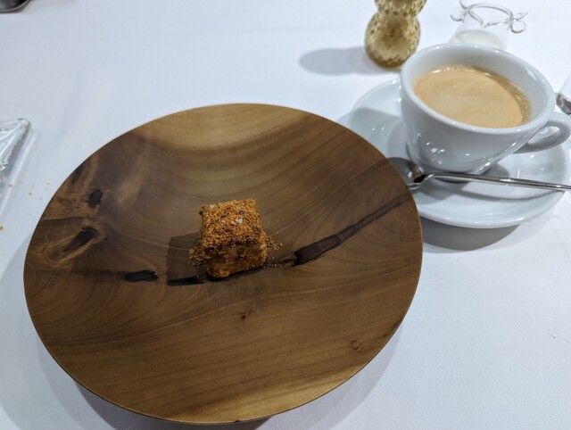 木工皿にちょこんと置かれた一口小菓子と香ばしい食後のエスプレッソ