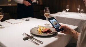 メインディッシュをスマートフォンで撮影する手元のシーン