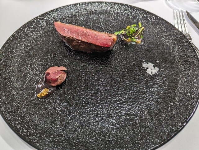 黒い大皿にシンプルに引き立つ絶妙なロゼカラーに焼き上げられた肉料理