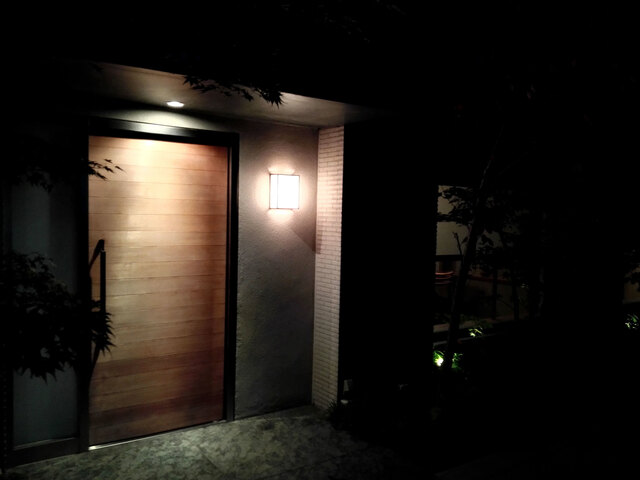 赤坂・六本木エリアに位置する最高峰の日本料理店「松川」の静謐な灯りが照らす木製のエントランスドア