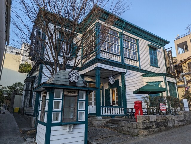 北野異人館街に佇む明治時代の洋館(北野物語館)を使用した「スターバックス・コーヒー 神戸北野異人館店」の緑と白のエントランス景観